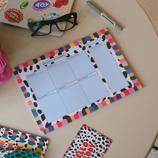 Rainbow weekly planner viewed from above, with colourful borders, glasses and a pen.