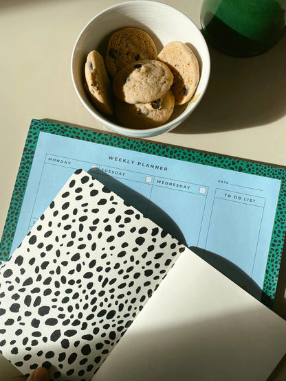 Open Dalmatian notebook showing spotted endpapers and a blank ivory page beside a matching planner.