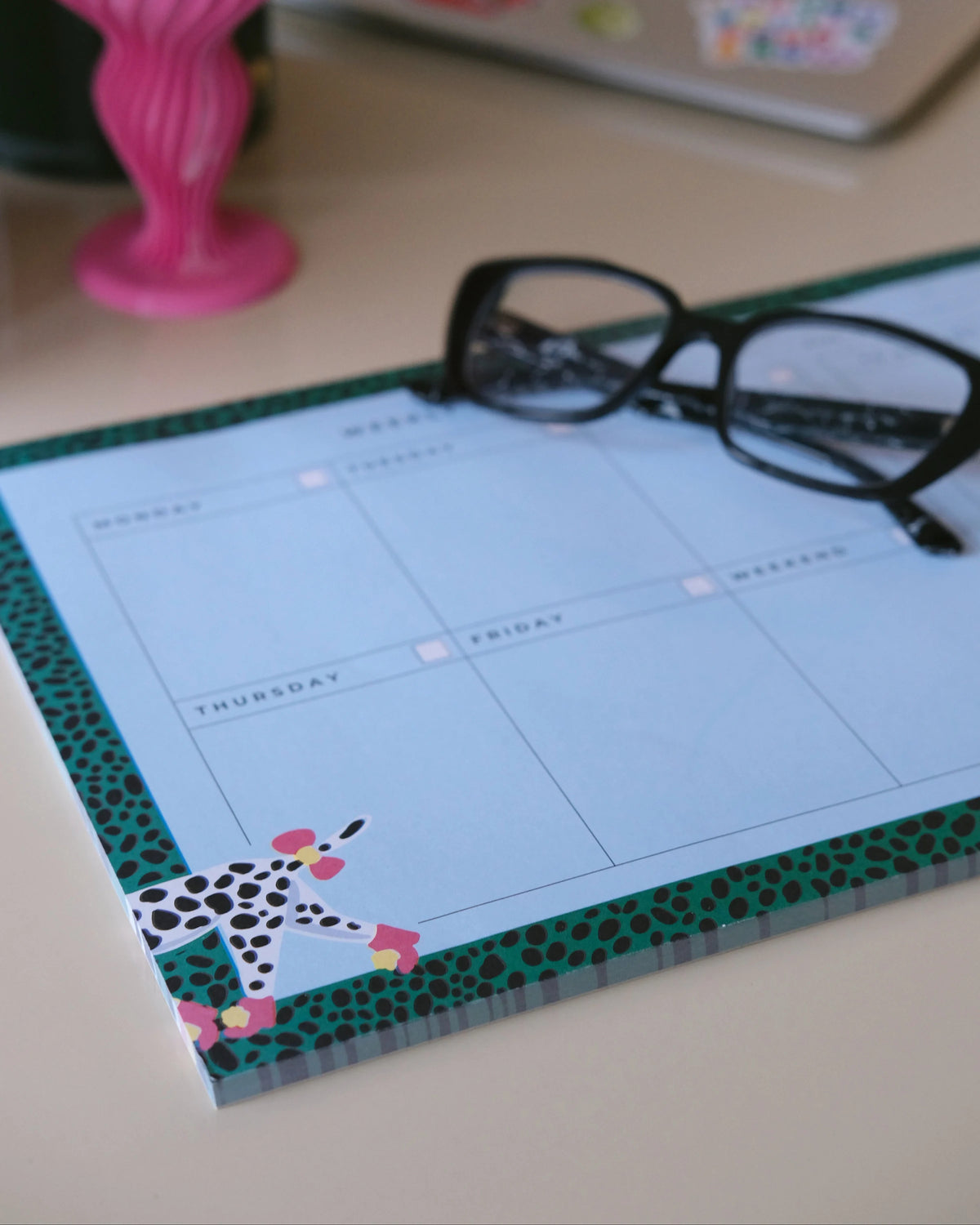 Dalmatian weekly planner on a desk with glasses above the weekly writing layout.