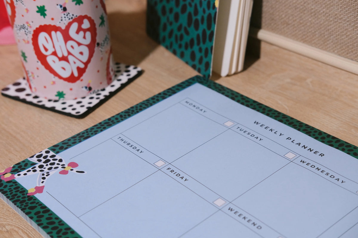 Close-up of the Dalmatian weekly planner showing writing sections and its green spotted border.