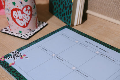 Close-up of the Dalmatian weekly planner showing writing sections and its green spotted border.