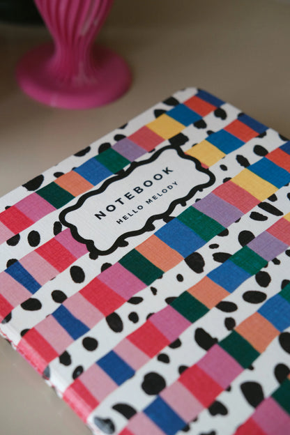 Close-up of the Rainbow notebook cover with colourful stripes and black spotted details.