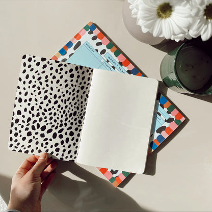 Open Rainbow notebook showing spotted endpapers and an ivory page above a matching planner.